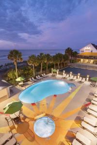 默特尔比奇Surfside Beach Oceanfront Hotel的一个带椅子和遮阳伞的游泳池以及大海