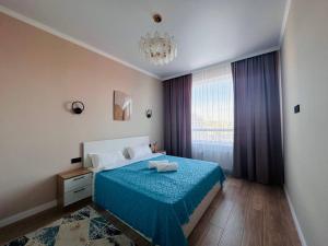 塔尔迪科尔Уютный уголок в центре города Grand Turan的一间卧室配有蓝色的床和吊灯。