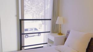二世古Niseko White Villas1的卧室配有一张床,外面设有窗户,外面设有汽车