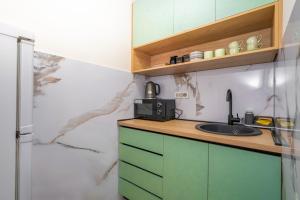 波德戈里察7 Hills Suites的厨房配有绿色橱柜和水槽
