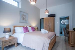 布雷肯Suite 12 - Sleeping Giant Hotel - Pen Y Cae Inn的一间卧室配有一张带粉红色枕头的床和一张桌子