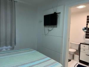 布卢梅瑙Suítes e quartos no Centro de Blumenau的卧室配有一张床,墙上配有电视。