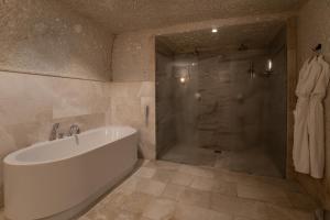 格雷梅Artemis Cave Suites & Spa- Adults Only的设有带浴缸和淋浴的浴室。