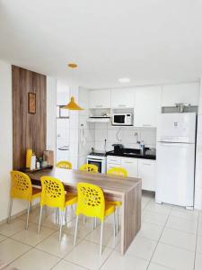 马塞约Ap. Novo Maceió - praia de Ponta verde的厨房配有木桌和黄色椅子