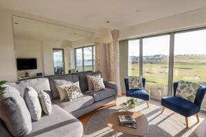 纽基Newquay Fistral Beach View的客厅配有灰色的沙发和2把蓝色的椅子