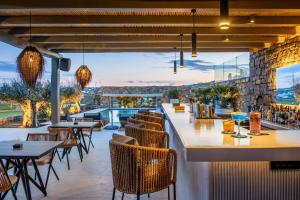 帕诺尔莫斯米科诺斯Panormos Bay Suites Luxury Resort的餐厅享有游泳池的景致,配有桌椅