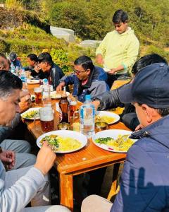 MahānkālSindhu Organic Agro And Farmstay的一群坐在餐桌上吃食物的人