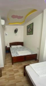 芹苴Nhà nghỉ Nam Anh的卧室配有两张床,墙上挂着黄色画作