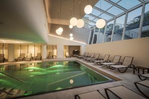 巴特霍夫加施泰因Hotel Norica - Thermenhotels Gastein mit dem Bademantel direkt in die Therme的一座带椅子和泳池的游泳池