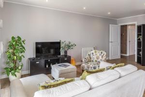 伦敦Lovely 3BR Penthouse wBalconies, Poplar, 2min DLR的客厅配有2张白色沙发和电视
