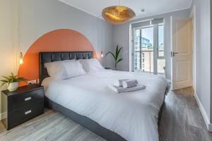 伦敦Lovely 3BR Penthouse wBalconies, Poplar, 2min DLR的卧室设有一张白色大床和大窗户