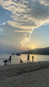 邦比尼亚斯Casa em Zimbros - DISPONÍVEL CARNAVAL的一群人在日落时分在海滩上玩耍