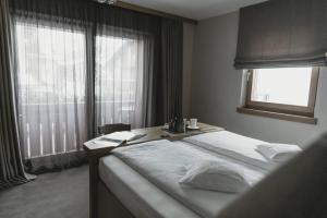 利维尼奥Eco & Wellness Boutique Hotel Sonne的一间卧室配有一张带桌子和窗户的床