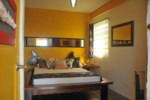 Saint Joseph芒果岛小屋酒店的一间卧室设有一张床和黄色的墙壁