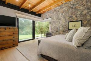 El PedregalHermosa Casa frente a campo de golf的一间卧室设有一张大床和石墙