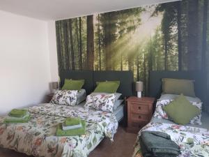GüimeVilla Feliza的一间卧室设有两张床,并拥有森林壁画