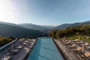 马兰扎Panoramahotel Huberhof的一个带椅子的游泳池,背景是山脉