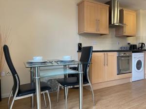 谢菲尔德1 BED MODERN APARTMENT WITH FREE PARKING, SHEFFIELD CITY CENTRE的厨房配有玻璃桌和椅子