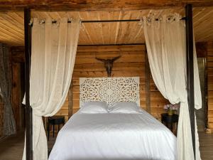 里耶巴斯蒂德马赞旅馆的一间卧室配有一张带白色床单和窗帘的床