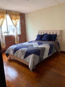 洛哈Dulce Hogar 01的一间卧室配有一张带蓝色枕头的床和一扇窗户。