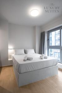 塞萨洛尼基WeStay Apartments, The Luxury Suites的卧室配有一张带白色床单的大床和窗户。