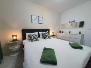 布拉索夫GREEN Apartment Coresi的卧室配有一张带两个绿色枕头的大型白色床