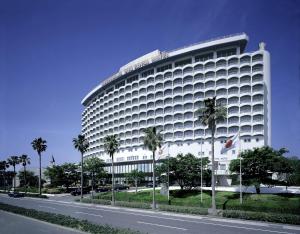 鹿儿岛鹿儿岛太阳皇家酒店的一条大白色的建筑,在道路前有棕榈树