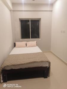 根尼亚古马里Shanmuga Residency的白色客房的一张床位,设有窗户