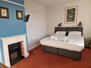法弗舍姆Railway Hotel的一间卧室配有一张床和一个壁炉