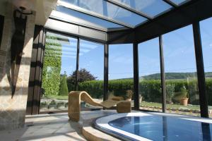 维奈Hostellerie Briqueterie & Spa Champagne的一座带大窗户的房屋内的游泳池