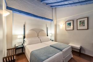 格拉纳达卡萨莫里斯卡酒店的卧室配有一张白色大床和蓝色天花板