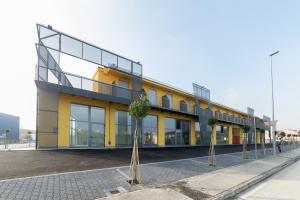 卡梅拉诺ASPIO RESIDENCE的一座棕榈树的黄色建筑