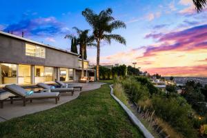 洛杉矶Hollywood Hills Luxury Modern Home with Pool & Sunset views的日落时分配有沙发和棕榈树的房子