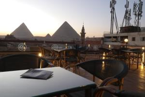 开罗Loca Pyramids View的配有桌椅的餐厅享有金字塔的景色