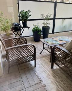 吕埃尔-马尔迈松Cozy Apartment Near the Train Station的天井配有两把椅子、一张桌子和盆栽植物