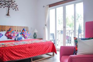 布塞里亚斯Refugio del Mar Luxury Hotel Boutique的一间卧室配有一张红色的床和一把椅子
