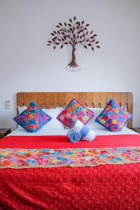 布塞里亚斯Refugio del Mar Luxury Hotel Boutique的一张红色的床,配有枕头,墙上有一棵树