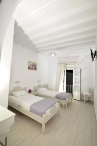 米克诺斯城迪米特拉膳食公寓的配有白色墙壁和木地板的客房内的两张床