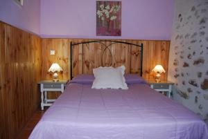 MaelloArroyo Milano Casa Rural的一间卧室配有一张带两张桌子的紫色床