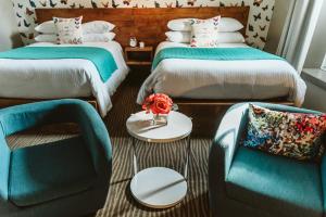 KingsvilleThe Grove Hotel的客房设有两张床、椅子和桌子。