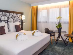 巴黎巴黎凡尔赛门展览中心美居酒店的酒店客房设有一张大床和一张桌子。