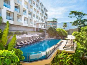 芭东海滩Andaman Beach Hotel Phuket - Handwritten Collection的酒店游泳池设有躺椅和遮阳伞