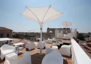 维罗纳Hotel Milano & SPA***S的屋顶甲板配有白色的桌椅和遮阳伞