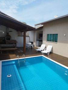邦比尼亚斯Casa com piscina em Zimbros的一个带两把椅子的游泳池以及一座房子