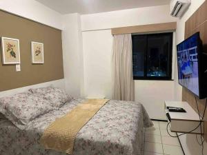 圣路易斯Flat Biarritz em São Luís com excelente localização!的一间卧室配有一张床、一台电视和一个窗口