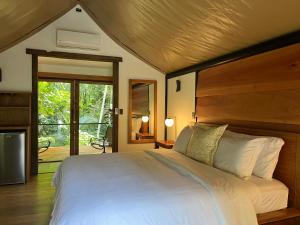 福尔图纳Hotel Arenal Glamping的卧室配有一张白色大床和木制床头板
