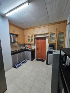 哥打巴鲁Ruhani Homestay 3 KB - 4 Bedroom Fully Airconditioned with WIFI & Netflix的一个带木制橱柜和红色门的厨房