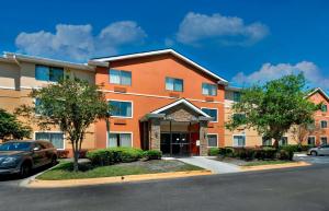 杰克逊维尔杰克逊维尔 - 勒努瓦大道南长住公寓式酒店的一座橙色的建筑,停车场有停车位