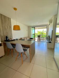 塔曼达雷Flat Beira Mar - Carneiros Beach Resort的厨房以及带木桌和椅子的客厅。