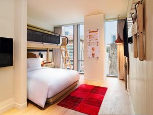 首尔Moxy Seoul Myeongdong的卧室配有白色的床和红色地毯。